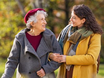 Old woman walking with a younger woman through a park in autumn