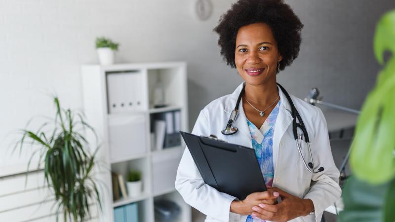 Medical doctor in office holding clipboard